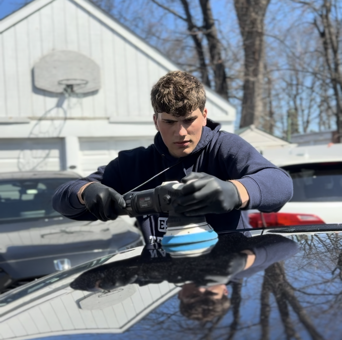 Evan polishing a vehicle with a machine polisher